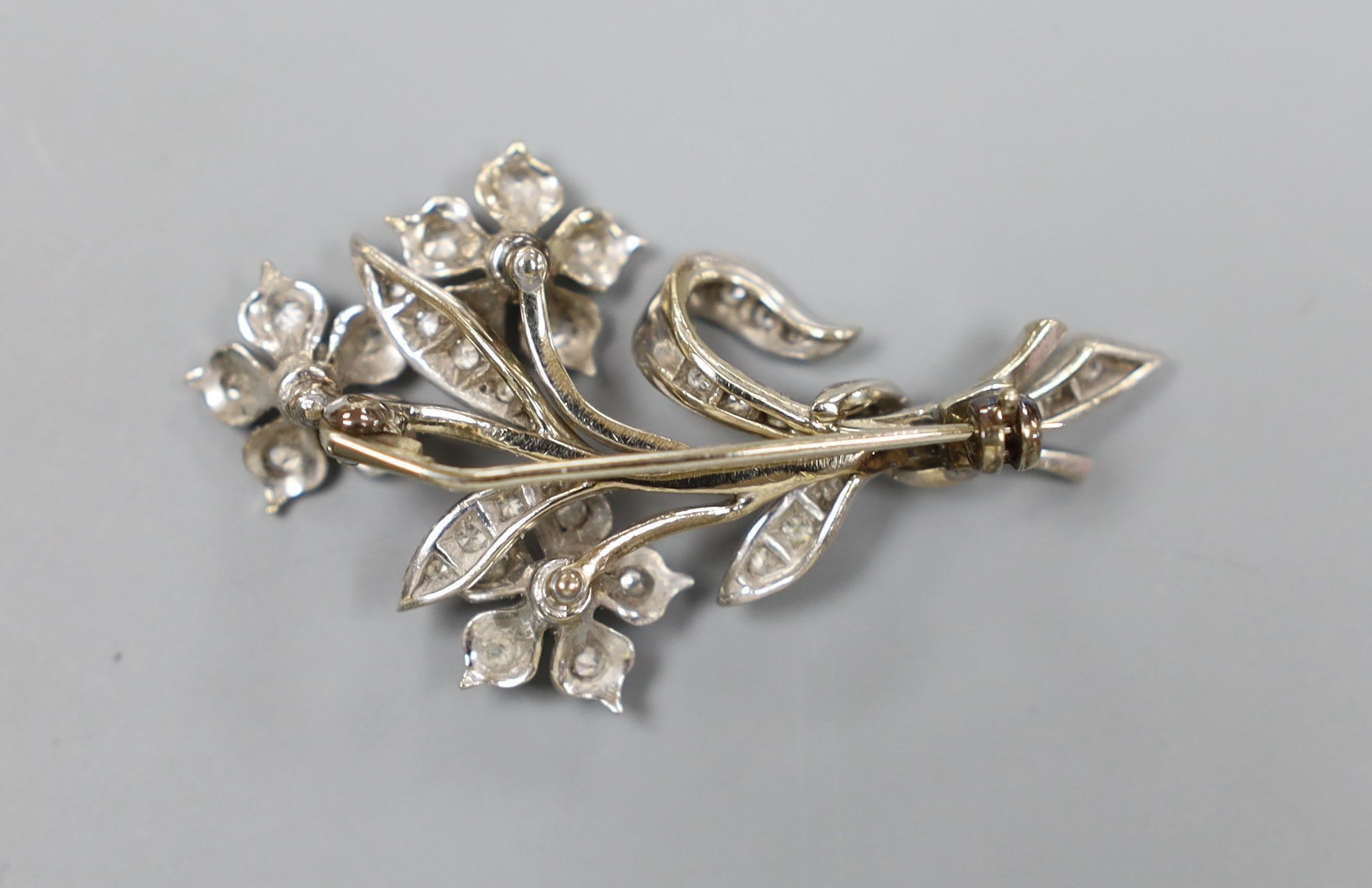 A 20th century white metal, emerald and diamond set spray brooch, 45mm, gross 10 grams.